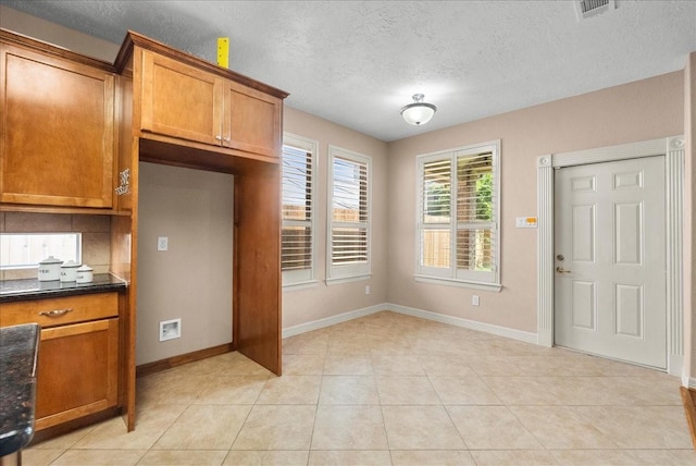 3707 Charleston St, Houston, TX 77021 - kitchen with brown cabinets, dark countertops, baseboards, a textured ceiling, and light tile patterned flooring