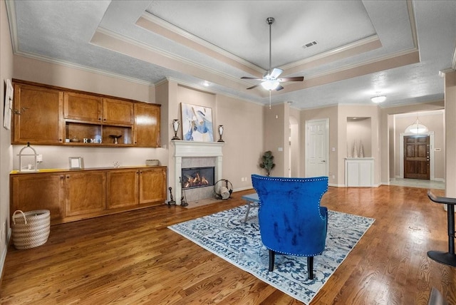 3707 Charleston St, Houston, TX 77021 - living area featuring a raised ceiling, wood finished floors, ornamental molding, a ceiling fan, and a fireplace