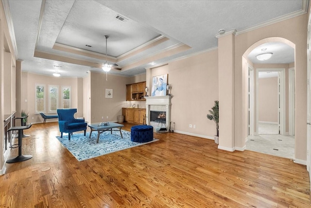 3707 Charleston St, Houston, TX 77021 - living area featuring ornamental molding, arched walkways, light wood finished floors, a fireplace, and a raised ceiling