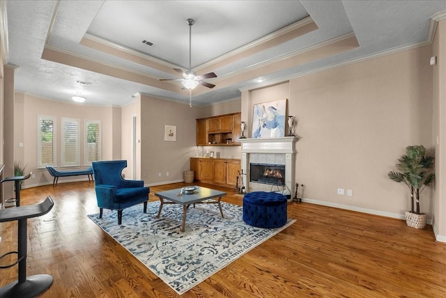3707 Charleston St, Houston, TX 77021 - living room with a tray ceiling, ornamental molding, light wood-type flooring, a tiled fireplace, and baseboards