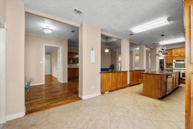 3707 Charleston St, Houston, TX 77021 - kitchen featuring double oven, a sink, brown cabinetry, dark countertops, and a textured ceiling