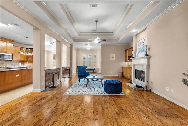 3707 Charleston St, Houston, TX 77021 - living area with a fireplace with flush hearth, a raised ceiling, light wood-type flooring, crown molding, and ceiling fan