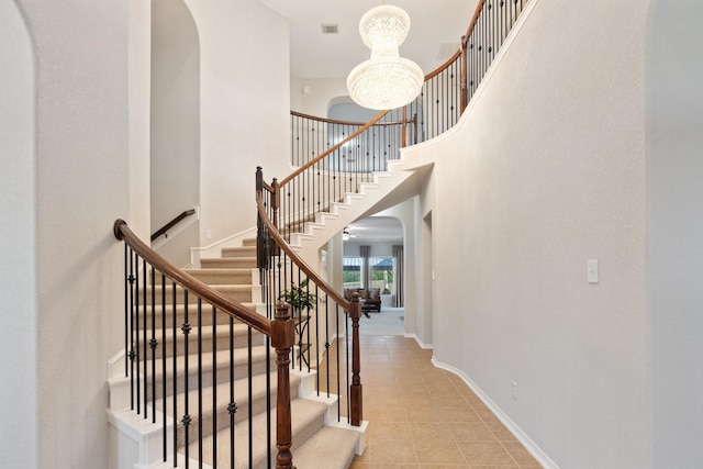 2153 Summit Mist Dr, Conroe, TX 77304 - stairway featuring arched walkways, a chandelier, tile patterned flooring, a towering ceiling, and baseboards