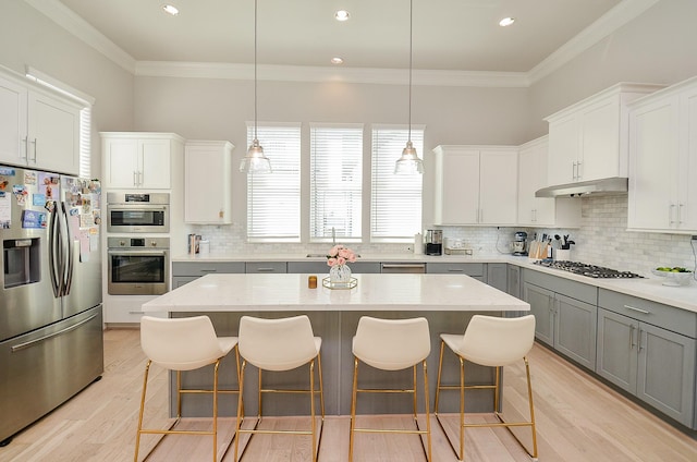 2419 W Kolbe Ln, Houston, TX 77080 - kitchen featuring appliances with stainless steel finishes, gray cabinets, under cabinet range hood, decorative backsplash, and a kitchen breakfast bar