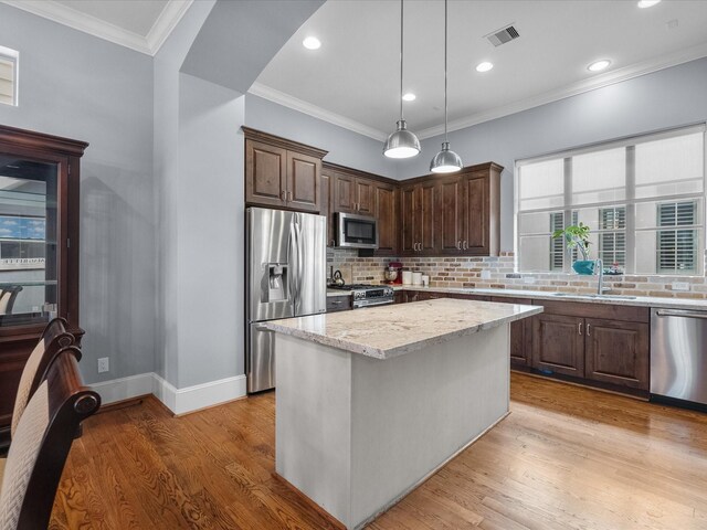1616 Rosewood St, Houston, TX 77004 - kitchen with appliances with stainless steel finishes, tasteful backsplash, dark brown cabinetry, light stone countertops, and light wood-style flooring