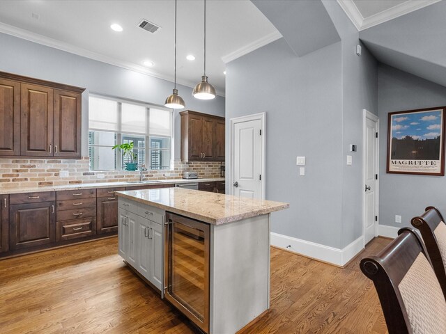 1616 Rosewood St, Houston, TX 77004 - kitchen with wine cooler, dark brown cabinets, ornamental molding, decorative backsplash, and light stone counters