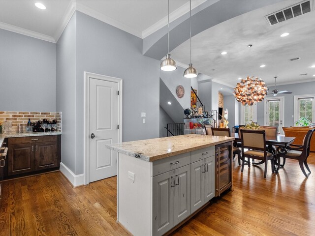 1616 Rosewood St, Houston, TX 77004 - kitchen with wine cooler, a ceiling fan, light wood-style floors, crown molding, and a kitchen island