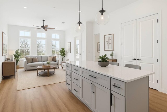 11120 Savannah Woods Ln, Houston, TX 77043 - kitchen featuring a ceiling fan, light wood finished floors, pendant lighting, light countertops, and a kitchen island