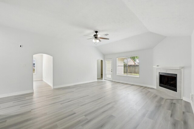 2707 Shawna Lyn Dr, Spring, TX 77373 - unfurnished living room with arched walkways, ceiling fan, a tile fireplace, light wood-type flooring, and vaulted ceiling