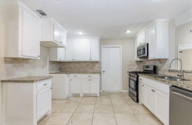 5807 Silver Forest Dr, Houston, TX 77092 - kitchen with stainless steel appliances, light stone counters, decorative backsplash, white cabinets, and recessed lighting