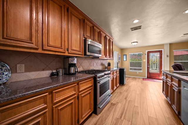 2223 Caroline Park Ln, Spring, TX 77386 - kitchen featuring appliances with stainless steel finishes, brown cabinets, light wood finished floors, a sink, and recessed lighting
