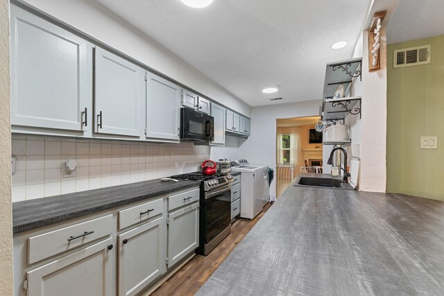 6506 Kentwick Dr, Houston, TX 77084 - kitchen featuring stainless steel range with gas cooktop, separate washer and dryer, black microwave, a sink, and tasteful backsplash