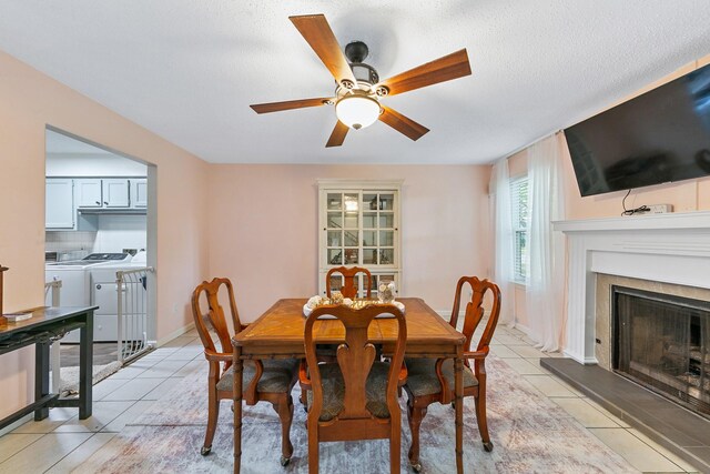 6506 Kentwick Dr, Houston, TX 77084 - dining area featuring light tile patterned floors, a ceiling fan, a fireplace with raised hearth, and a textured ceiling