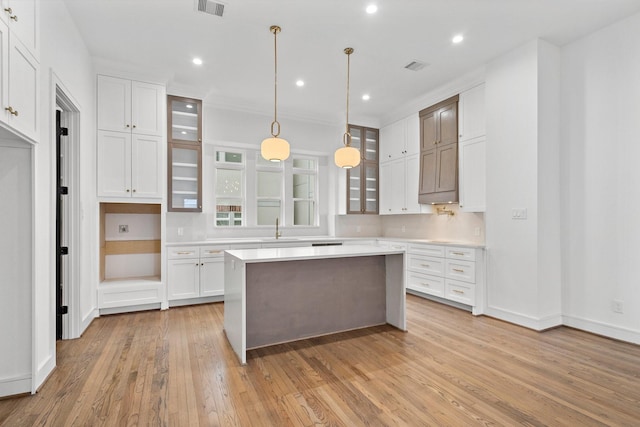 1013 E 28th St, Houston, TX 77009 - kitchen with a sink, glass insert cabinets, light countertops, light wood finished floors, and white cabinetry