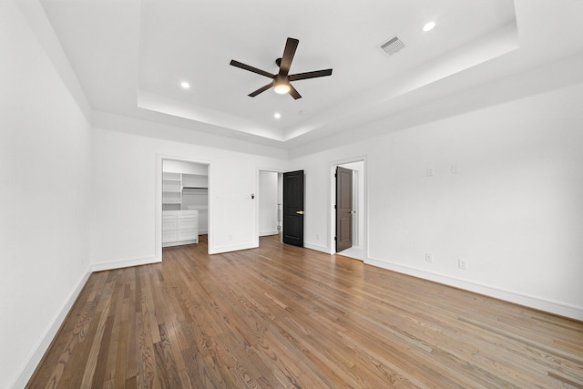 1013 E 28th St, Houston, TX 77009 - unfurnished bedroom with a tray ceiling, wood finished floors, baseboards, recessed lighting, and a ceiling fan