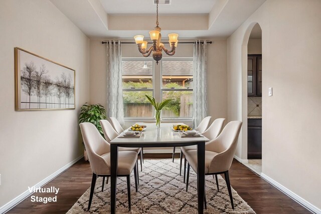 122 Jacobs Meadow Dr, Conroe, TX 77384 - dining space with arched walkways, a chandelier, a raised ceiling, and dark wood-type flooring