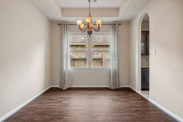 122 Jacobs Meadow Dr, Conroe, TX 77384 - unfurnished dining area featuring a chandelier, arched walkways, dark wood-style floors, a raised ceiling, and baseboards