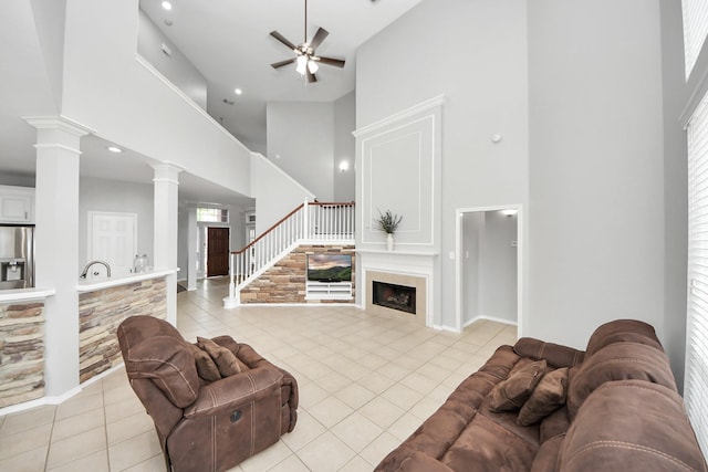 8742 Melting Shadows Ln, Houston, TX 77095 - living room with high vaulted ceiling, light tile patterned flooring, a ceiling fan, a fireplace, and decorative columns
