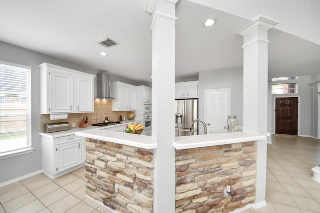 8742 Melting Shadows Ln, Houston, TX 77095 - kitchen with wall chimney exhaust hood, ornate columns, stainless steel refrigerator with ice dispenser, and light tile patterned floors