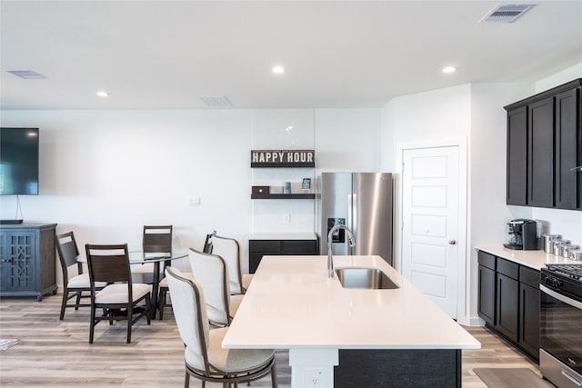 12327 Brandenburg Gate Dr, Houston, TX 77047 - kitchen with stainless steel appliances, a sink, light countertops, light wood-style floors, and a center island with sink