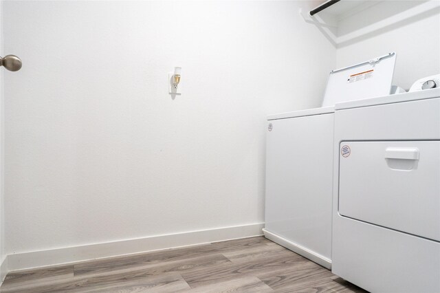 12327 Brandenburg Gate Dr, Houston, TX 77047 - laundry area featuring washing machine and clothes dryer, light wood-style flooring, and baseboards