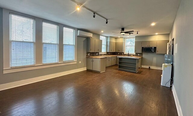236 8th St, Somerville, TX 77879 - kitchen with gray cabinetry, baseboards, an AC wall unit, a sink, and recessed lighting
