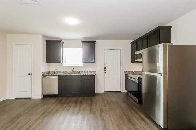 7945 Henson St, Houston, TX 77028 - kitchen with stainless steel appliances, dark wood-style flooring, baseboards, and light stone countertops