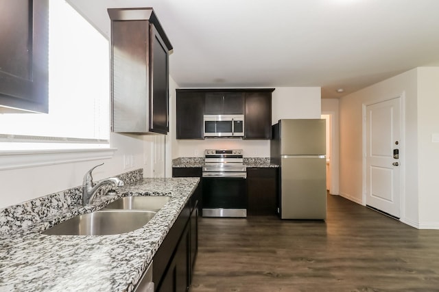 7945 Henson St, Houston, TX 77028 - kitchen with appliances with stainless steel finishes, a sink, dark wood-type flooring, light stone counters, and dark brown cabinetry