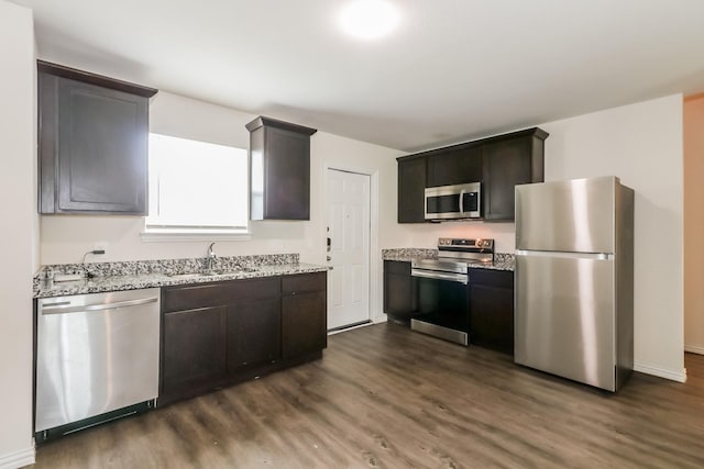 7945 Henson St, Houston, TX 77028 - kitchen with appliances with stainless steel finishes, a sink, dark wood finished floors, light stone countertops, and baseboards
