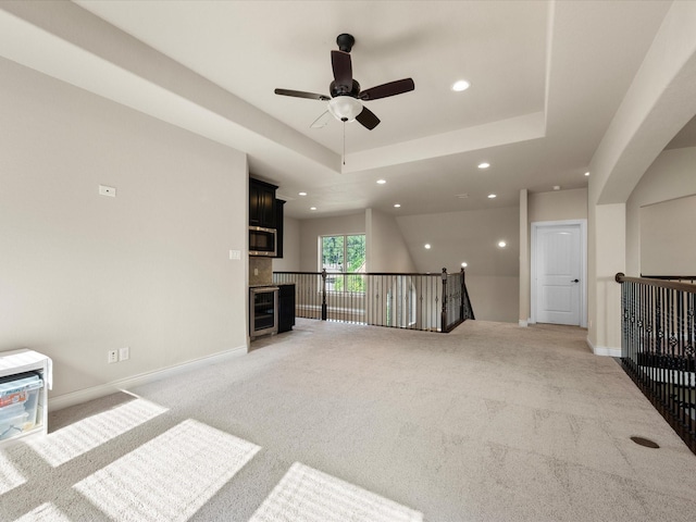 8322 Sands Bank Ln, Conroe, TX 77304 - unfurnished living room featuring wine cooler, ceiling fan, recessed lighting, light colored carpet, and a tray ceiling