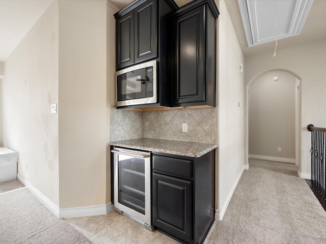 8322 Sands Bank Ln, Conroe, TX 77304 - kitchen featuring wine cooler, stainless steel microwave, decorative backsplash, and dark cabinetry