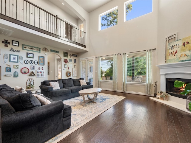 8322 Sands Bank Ln, Conroe, TX 77304 - living area featuring arched walkways, a towering ceiling, healthy amount of natural light, a glass covered fireplace, and dark wood-type flooring