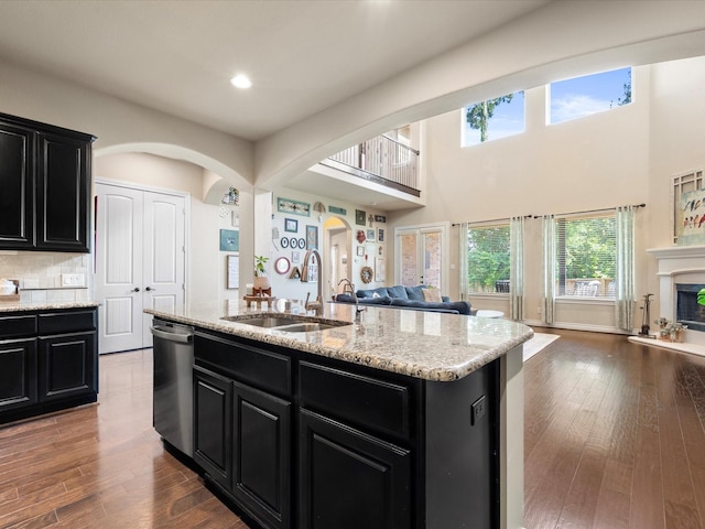 8322 Sands Bank Ln, Conroe, TX 77304 - kitchen featuring dark cabinetry, open floor plan, a sink, stainless steel dishwasher, and arched walkways