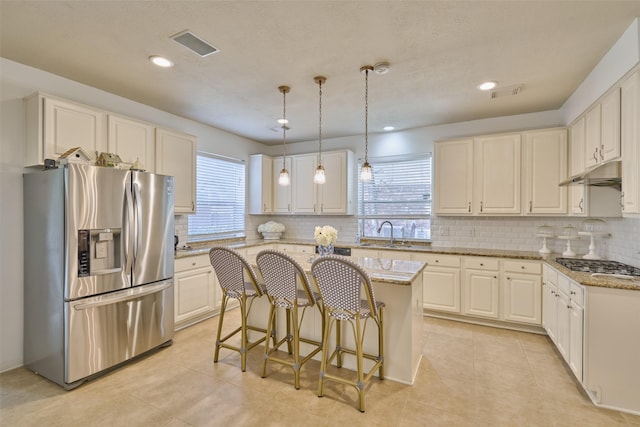 26 E Sterling Pond Cir, The Woodlands, TX 77382 - kitchen featuring appliances with stainless steel finishes, a center island, light stone countertops, tasteful backsplash, and recessed lighting
