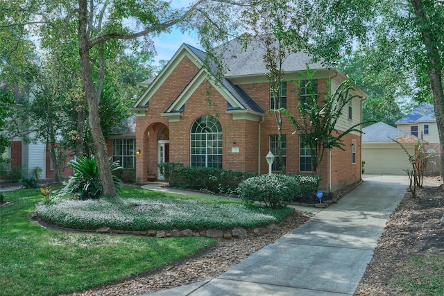 26 E Sterling Pond Cir, The Woodlands, TX 77382 - view of front of home with brick siding, an outdoor structure, a shingled roof, and a front lawn