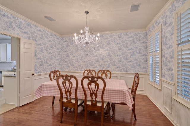26 E Sterling Pond Cir, The Woodlands, TX 77382 - dining area with wood finished floors, a chandelier, a wainscoted wall, crown molding, and wallpapered walls