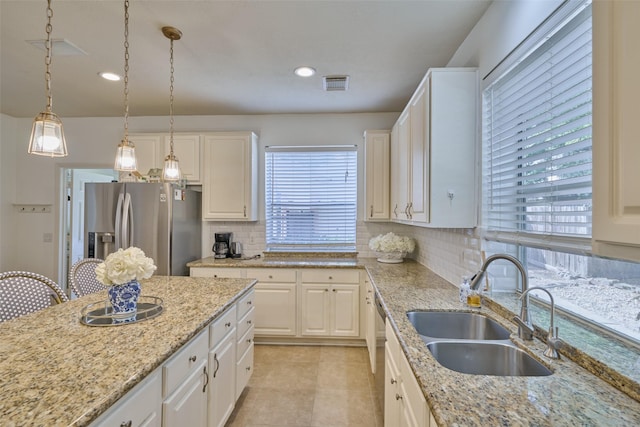 26 E Sterling Pond Cir, The Woodlands, TX 77382 - kitchen featuring appliances with stainless steel finishes, a sink, tasteful backsplash, light stone counters, and decorative light fixtures