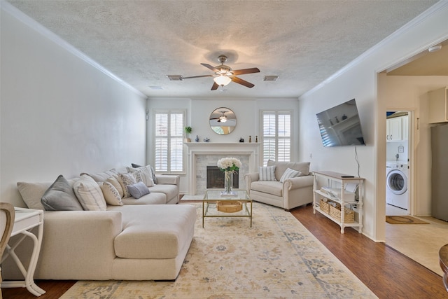 26 E Sterling Pond Cir, The Woodlands, TX 77382 - living room featuring washer / dryer, crown molding, ceiling fan, dark wood-style flooring, and a fireplace