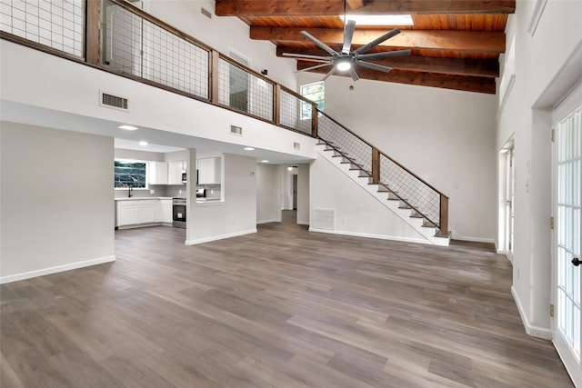 118 Glenview, Livingston, TX 77351 - unfurnished living room with a ceiling fan, baseboards, stairs, a towering ceiling, and dark wood finished floors