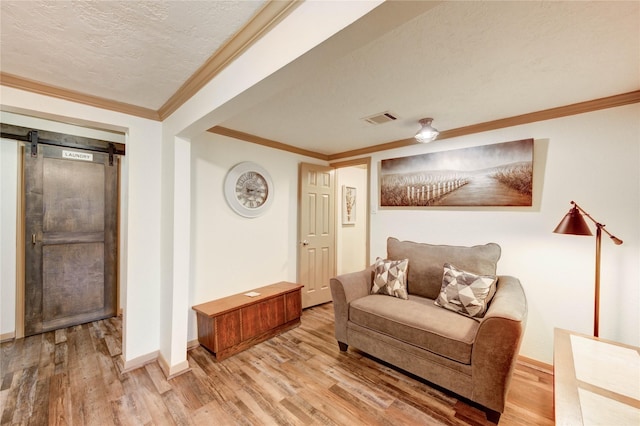 4603 New Orleans St, Houston, TX 77020 - living area with light wood-type flooring, baseboards, a barn door, crown molding, and a textured ceiling