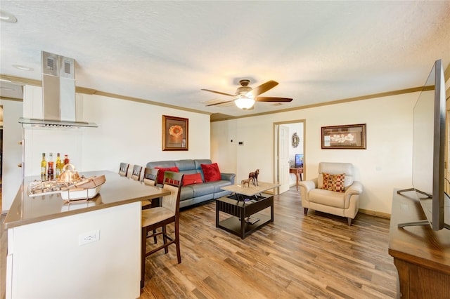 4603 New Orleans St, Houston, TX 77020 - living room featuring light wood-style flooring, ornamental molding, ceiling fan, a textured ceiling, and baseboards