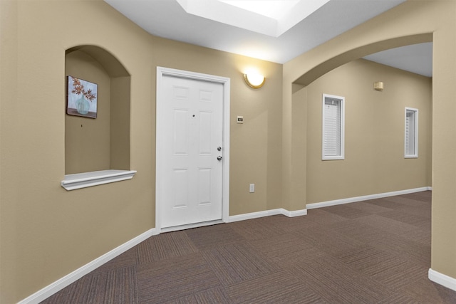 2815 Kings Crossing Dr Unit 102, Houston, TX 77345 - foyer featuring dark colored carpet, arched walkways, and baseboards