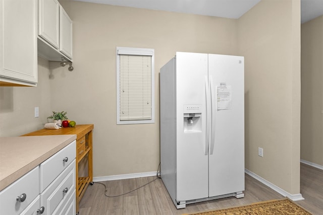 2815 Kings Crossing Dr Unit 102, Houston, TX 77345 - kitchen featuring white fridge with ice dispenser, light wood-style floors, light countertops, white cabinetry, and baseboards