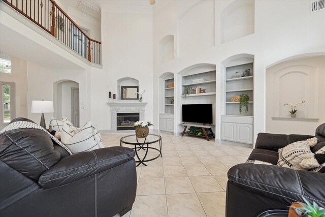 3505 Parkside Dr, Pearland, TX 77584 - living room with built in features, a towering ceiling, tile patterned floors, a glass covered fireplace, and crown molding