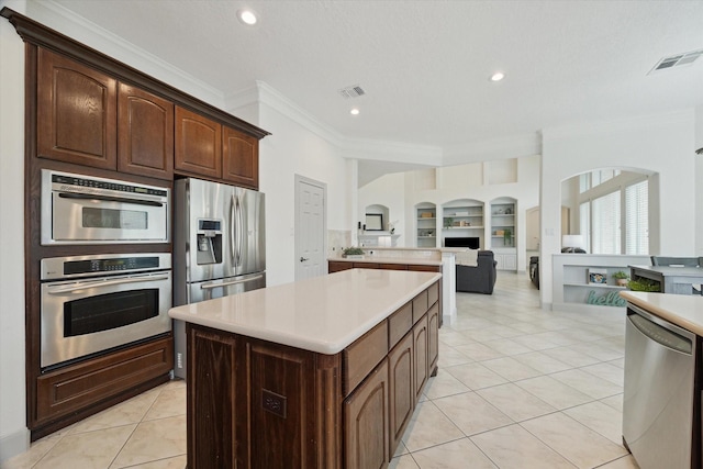3505 Parkside Dr, Pearland, TX 77584 - kitchen with stainless steel appliances, arched walkways, crown molding, built in features, and light countertops