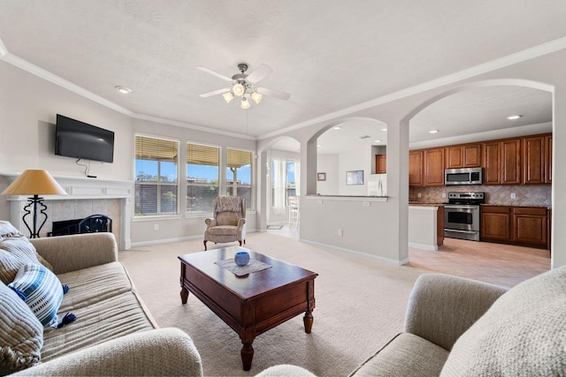 22610 Torrisdale Ln, Tomball, TX 77375 - living area featuring light colored carpet, ceiling fan, arched walkways, ornamental molding, and a tile fireplace