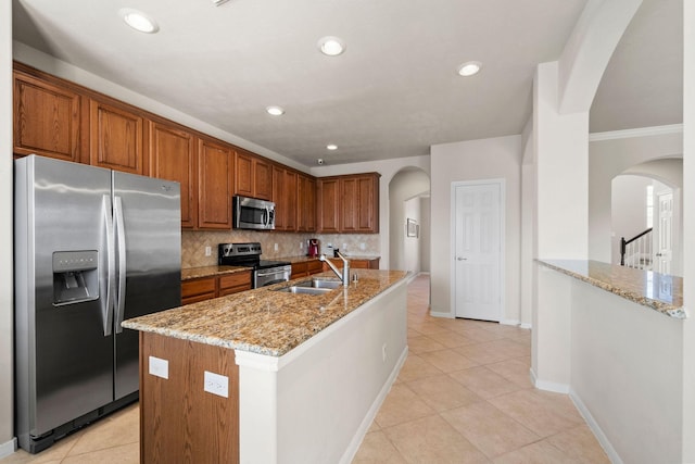 22610 Torrisdale Ln, Tomball, TX 77375 - kitchen with appliances with stainless steel finishes, arched walkways, light stone counters, brown cabinetry, and crown molding