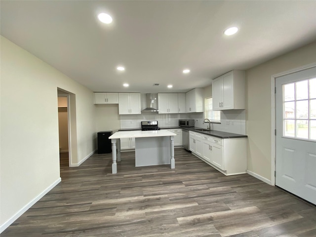 301 Old Bayou Dr, Dickinson, TX 77539 - kitchen featuring stainless steel appliances, wall chimney exhaust hood, white cabinets, recessed lighting, and a kitchen bar