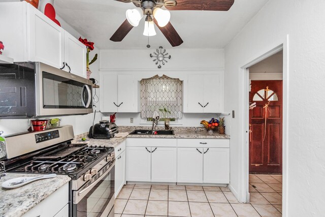 8209 Howard Dr, Houston, TX 77017 - kitchen with stainless steel appliances, a ceiling fan, a sink, light tile patterned floors, and white cabinets