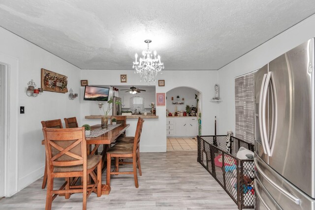 8209 Howard Dr, Houston, TX 77017 - dining room with a textured ceiling, ceiling fan, a chandelier, light wood-style flooring, and arched walkways